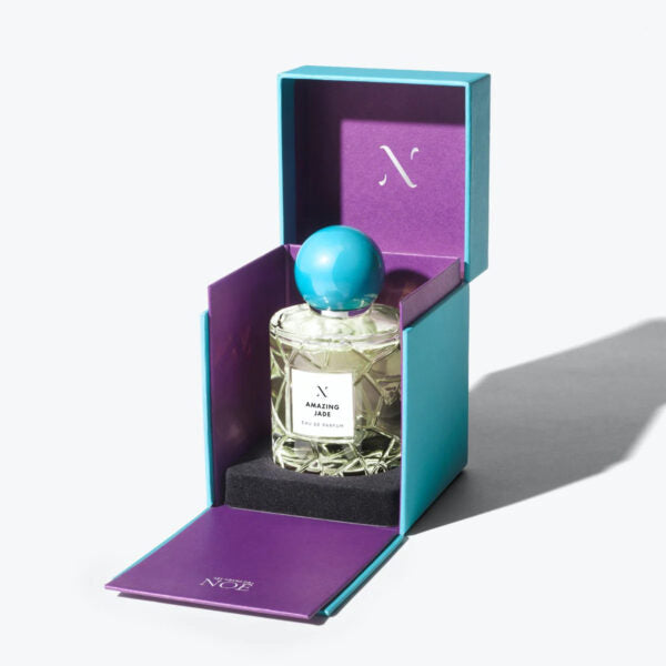 Perfume bottle with blue cap in a purple and teal box on a white background