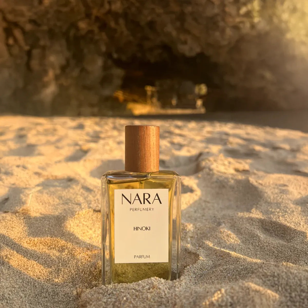 Nara Perfumery bottle on sand with cave in background