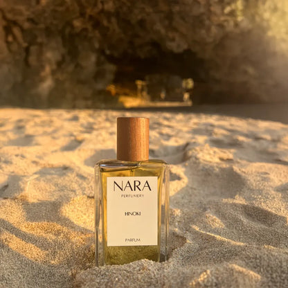 Nara Perfumery bottle on sand with cave in background