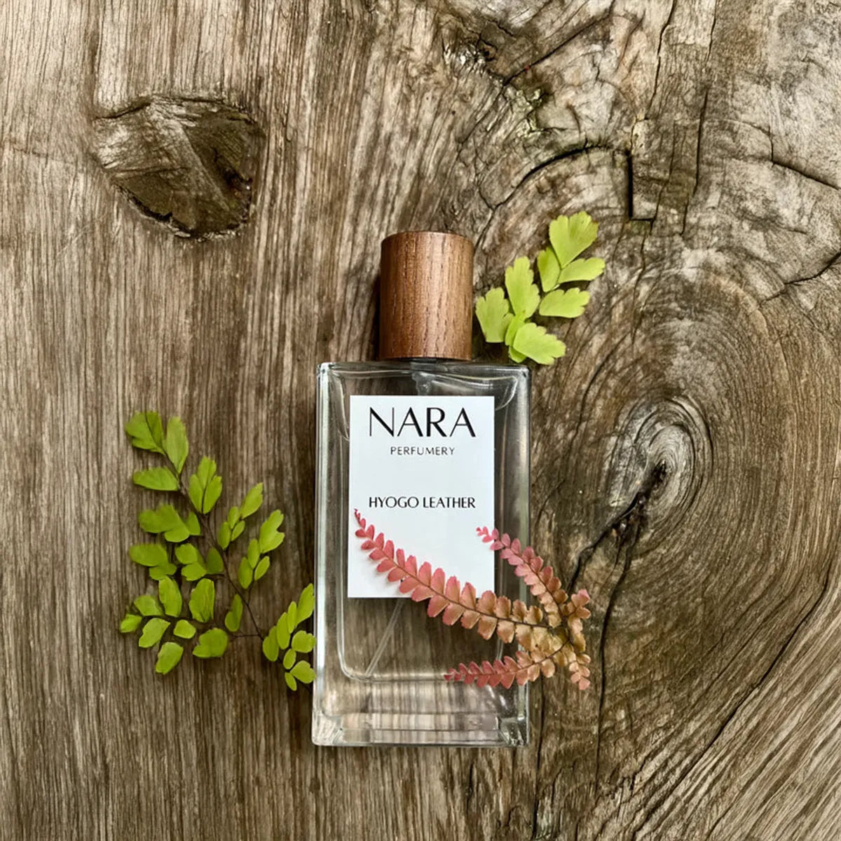 NARA perfume bottle on a wooden surface with leaves