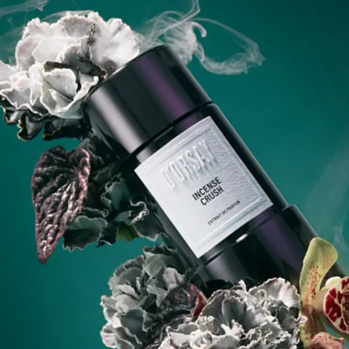 Perfume bottle labeled 'Incense Crush' surrounded by flowers and leaves on a teal background