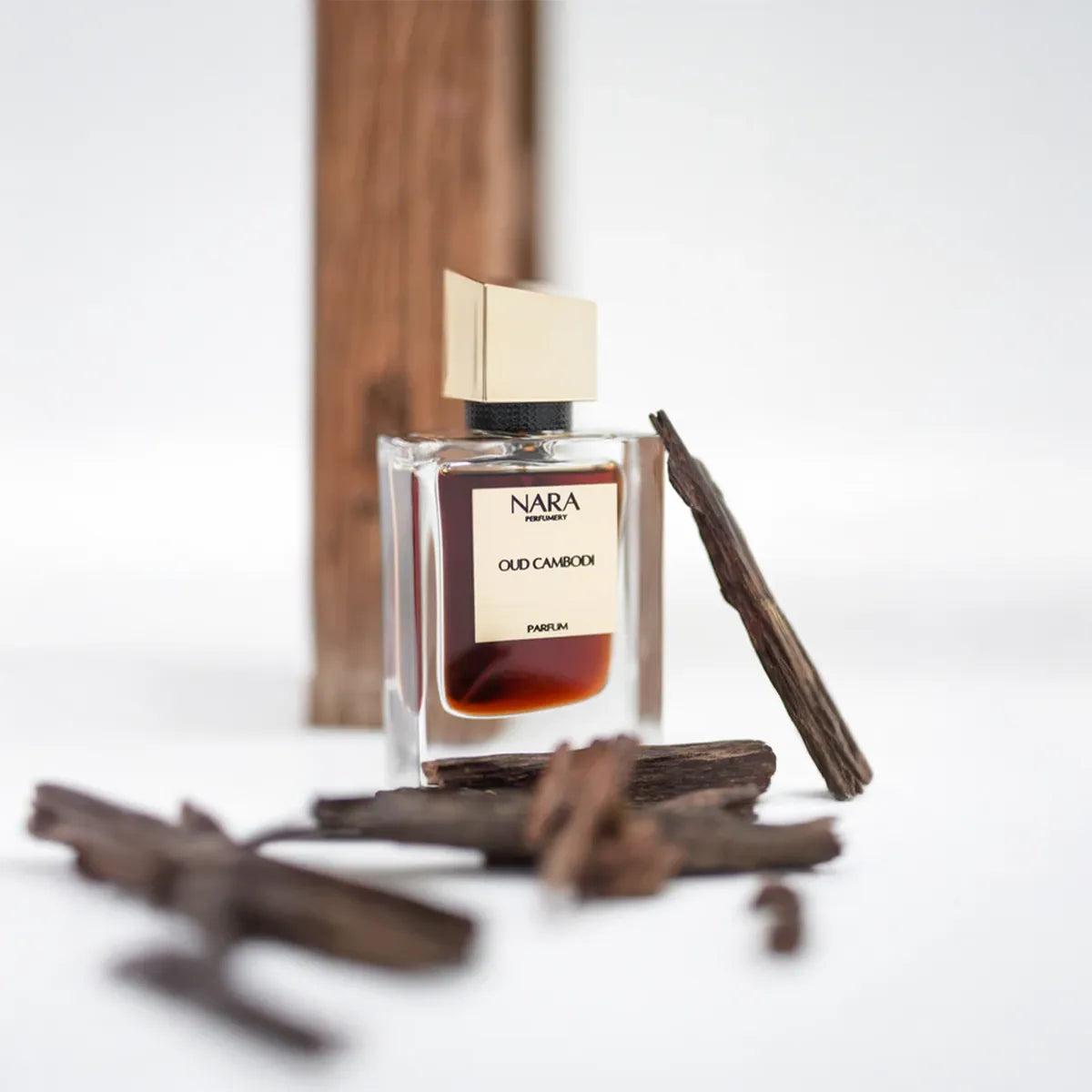 Nara Oud Cambodia perfume bottle with cinnamon sticks on a white background