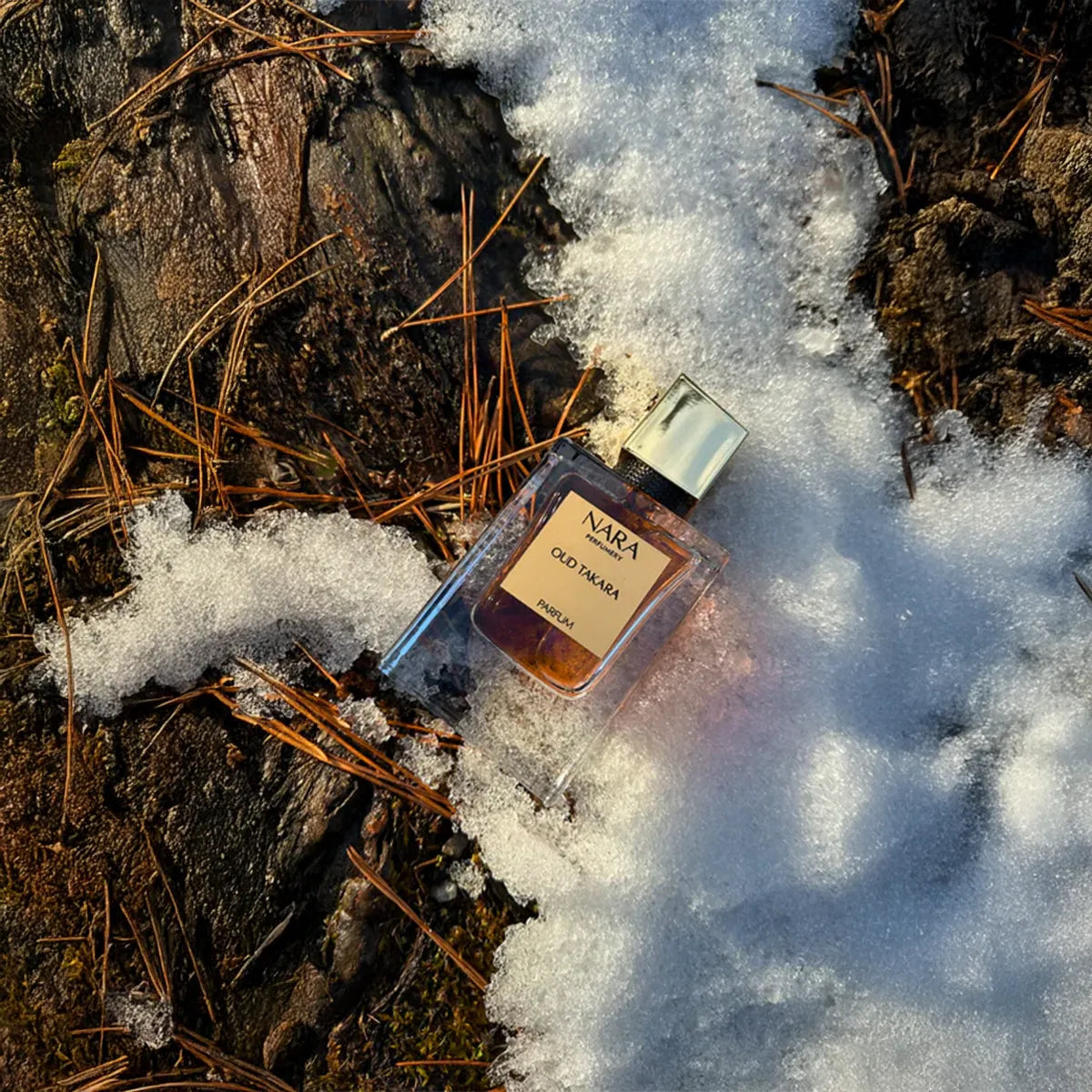 Nara Old Takara perfume bottle on a snowy ground with pine needles