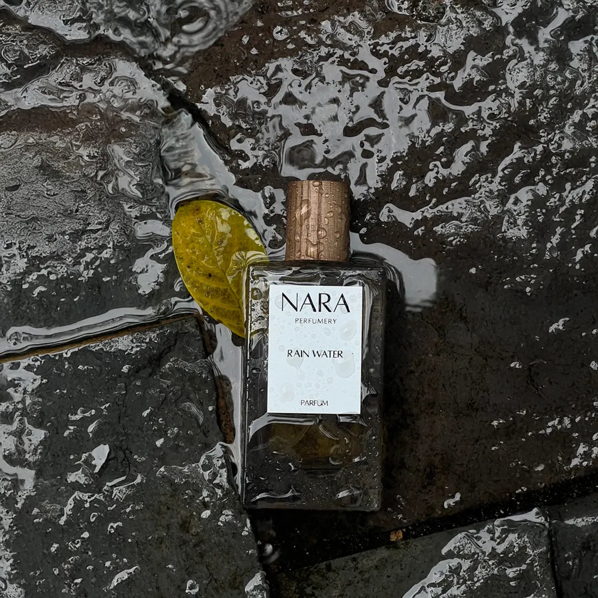 NARA Perfume bottle on a textured stone surface with water droplets.