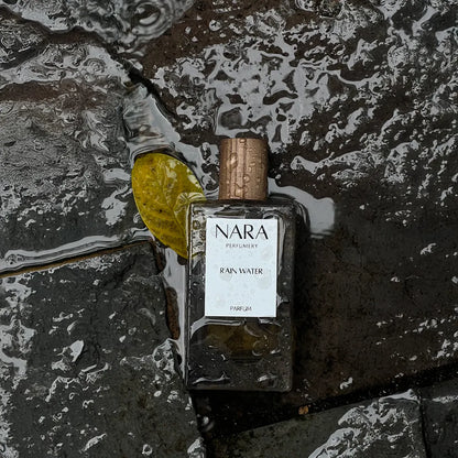 NARA Perfume bottle on a textured stone surface with water droplets.