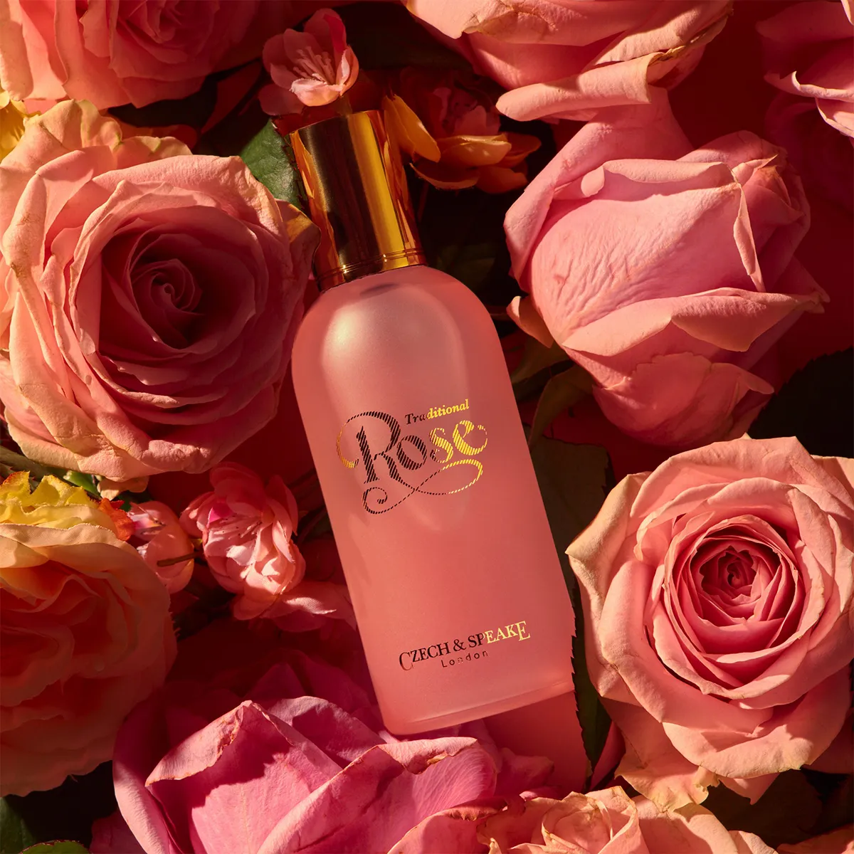 Pink bottle of 'Traditional Rose' perfume surrounded by pink roses