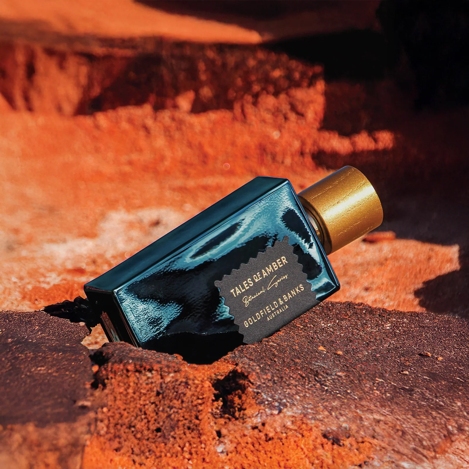 Perfume bottle labeled 'Tales of Amber' by Dolce & Gabbana on a textured orange surface.